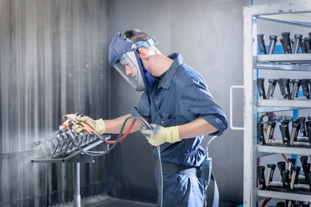 Worker paint spraying automotive parts in spray paint factory